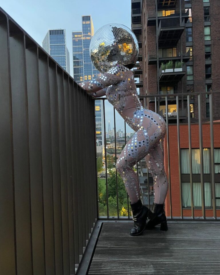 disco ball heads doing disco dancing at a rooftop pool, embassy gardens, london