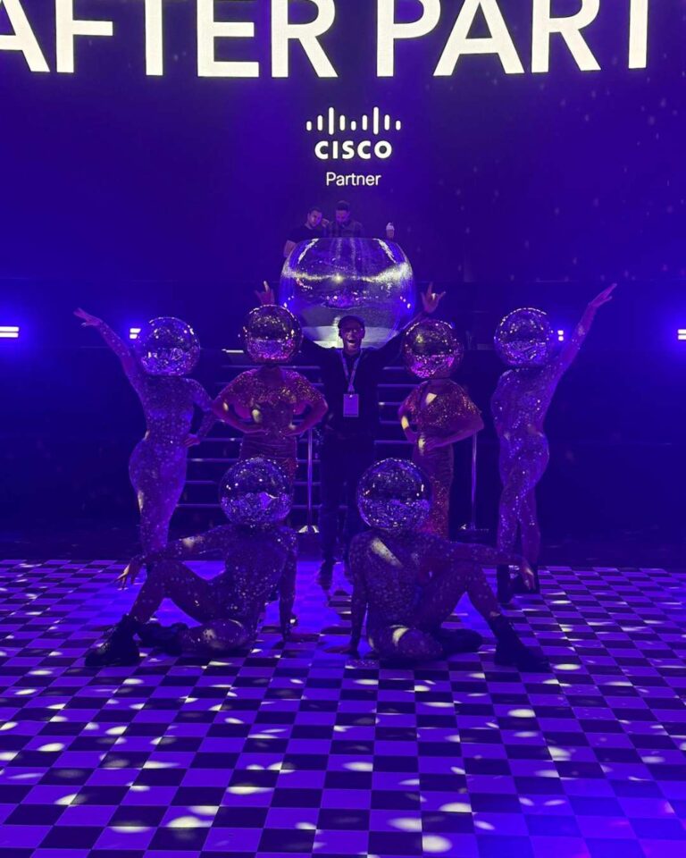 Softcat after party photo with gold and silver Disco Ball Head dancers in front of stage at NEC Birmingham