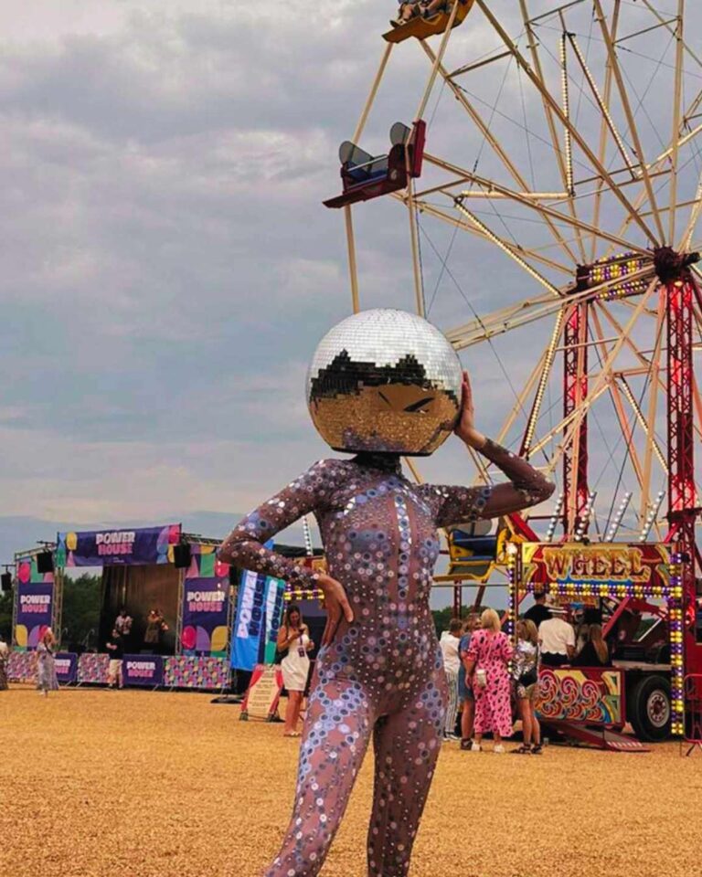 Disco Ball Head dancer posing in front of Ferris wheel at corporate family festival summer 2025